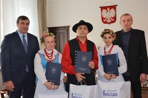 Na zdjęciu w gabinecie burmistrza stoi 5 osób. 3 osoby w tradycyjnych strojach dudziarskich oraz Burmistrz i dyrektor KOKu. (photo)